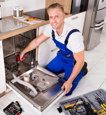 A man performing West Palm Beach appliance repair by fixing a dishwasher in a kitchen.
