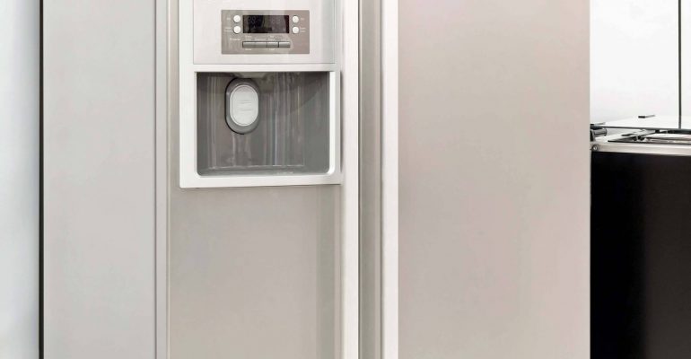 A stainless steel refrigerator is next to a washer and dryer.